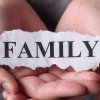 Auf diesem Foto sind zwei Hände abgebildet, die gemeinsam eine Fläche bilden und in diesen Handflächen liegt ein Papierschnipsel auf dem das Wort Family abgedruckt ist.