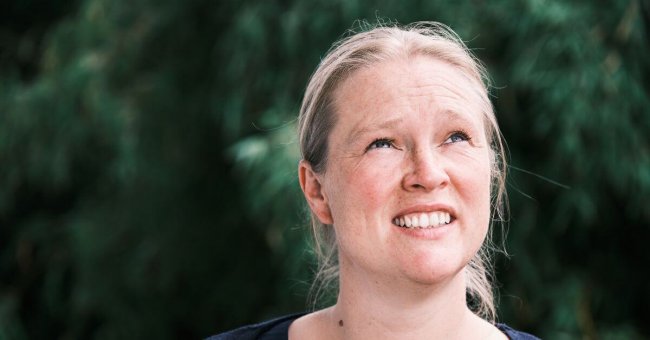 Annehmen, was ist Auf dem Bild bin ich zu sehen. Ich schaue etwas fragend in den Himmel. Hinter mir ist ein grüner Busch zu erahnen. Er ist verschwommen.