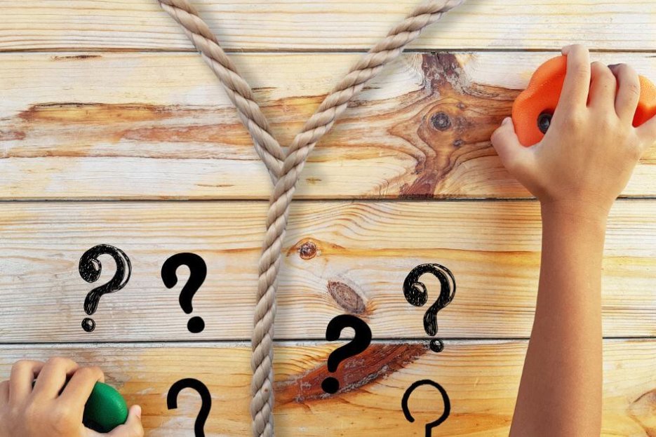 Das Foto zeigt ein Seil, dass sich trennt, zwei Hände an Bouldergriffen und viele Fragezeichen. Das Seil ist beige, die Fragezeichen schwarz, der linke Bouldergriff grün, der rechte orange. Im Hintergrund ist eine Holzwand zu erkennen, an der die Griffe befestigt sind.