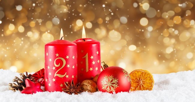 Advent Auf diesem Foto sind zwei rote Stumpenkerzen zu erkennen. Sie sind mit goldenen Zahlen und Sternen bedruckt. Mit 1 und 2. Um sie herum liegen Weihnachtsbaumkugel und Tannenzapfen. Das gesamte Arrangement liegt in Kunstschnee. Der Hintergrund ist golden und sieht nach Lichteffekt aus.