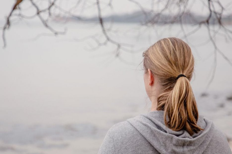 Auf dem Foto siehst du mich von hinten. Ich stehe an der Ostsee und schaue aufs Wasser. Es ist Herbst, es ist ein grauer Tag.. Ich habe halblange, dunkelblonde Haare und einen Pferdeschwanz. Ich trage eine graue Strickjacke mit Kapuze. Ich bin ab Höhe der Schulterblätter zu erkennen.