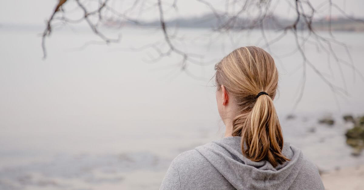 Coachingpraxis Claudia Süsens Auf dem Foto siehst du mich von hinten. Ich stehe an der Ostsee und schaue aufs Wasser. Es ist Herbst, es ist ein grauer Tag.. Ich habe halblange, dunkelblonde Haare und einen Pferdeschwanz. Ich trage eine graue Strickjacke mit Kapuze. Ich bin ab Höhe der Schulterblätter zu erkennen.