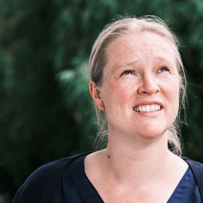 Ich stehe vor dem Bambusbusch und schaue etwas nachdenklich nach oben. Ich trage eine blaue Bluse und eine blaue Strickjacke. Mein Haar ist zu einem Knoten gebunden. Mein Haar ist dunkelblond.