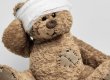Auf diesem Foto ist ein Teddybär abgebildet, der einen Kopfverband trägt und ein Pflaster auf dem Herzen hat.
