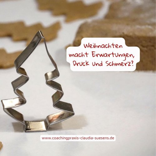 Hier ist ein verbogener Plätzchenausstecher abgebildet. Es ist eine Tannenbaum. Im Hintergrund sind bereits ausgestochene Plätzchen abgebildet und auch ein Teigrest.