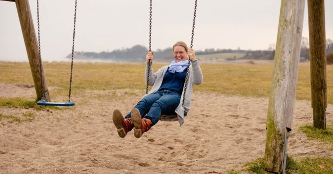 Selbstfürsorge vs. Selbstoptimierung Hier bin ich schaukelnder Weises abgebildet. Am Strand von Habernis. Eine große Schaukel aus Holz mit langen Ketten.
