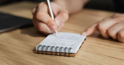 Hier schreibt eine Person auf einen kleinen Ringblock.